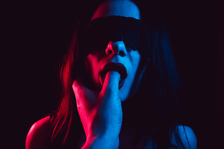 Frau mit Augenbinde und Finger im Mund