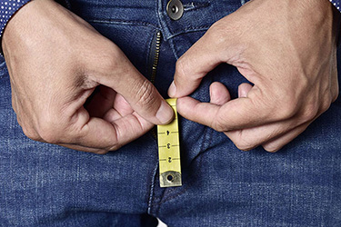 Mann mit Maßband, das aus seinem Hosenstall guckt